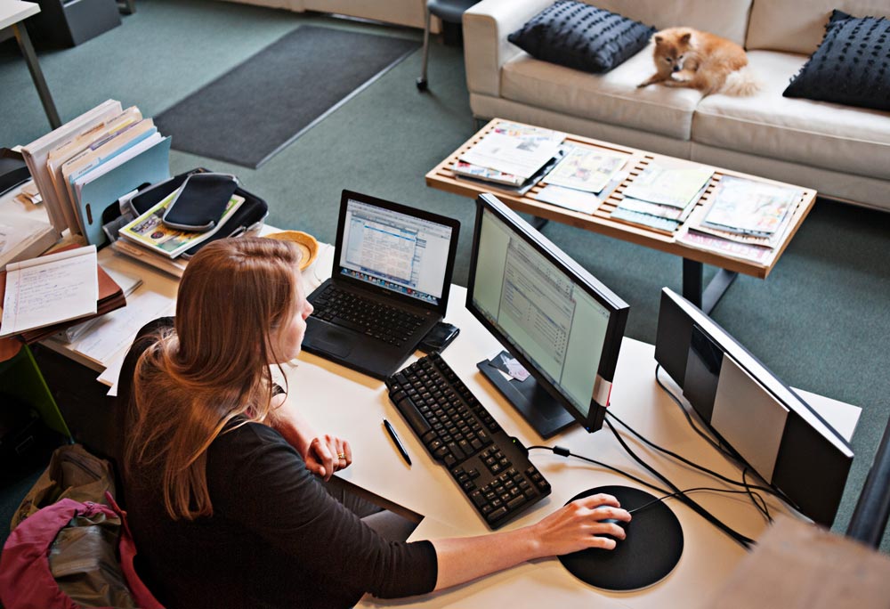 Kvinna som sitter framför datorskärmar på ett kontor